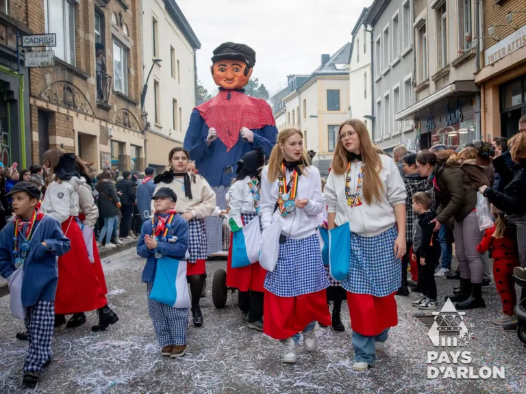 Groupe carnavalesque défilant avec le géant Jempi sur un char au carnaval d’Arlon