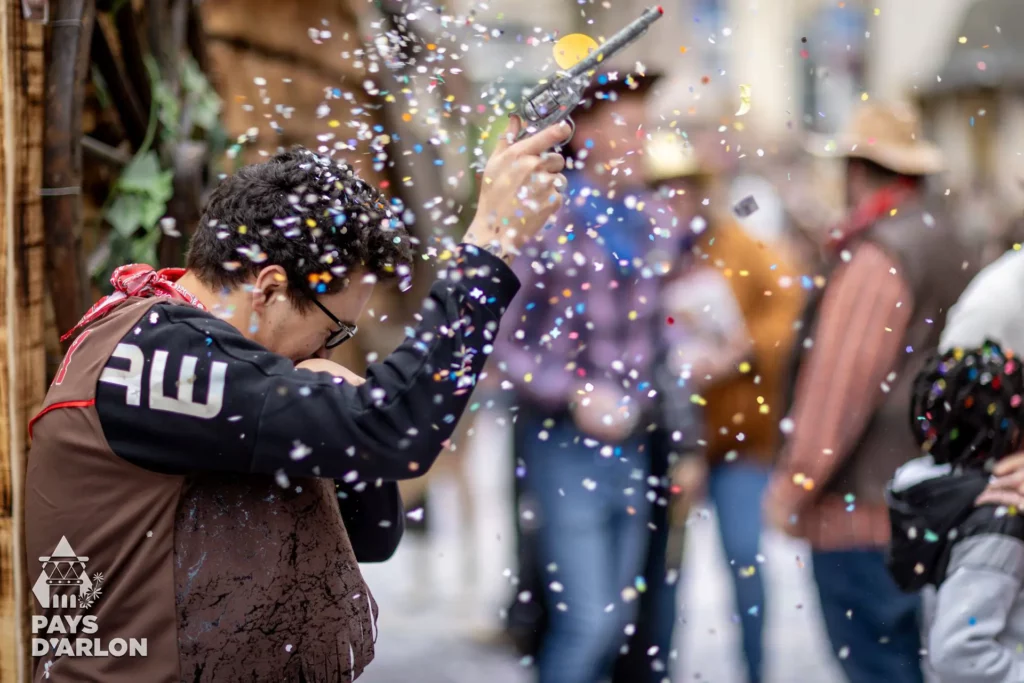 Participant déguisé en cowboy sous une pluie de confettis au carnaval d’Arlon
